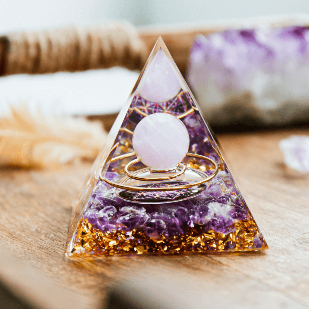Orgonite piramidal de resina com esfera de cristal, pedras ametista e detalhes dourados.