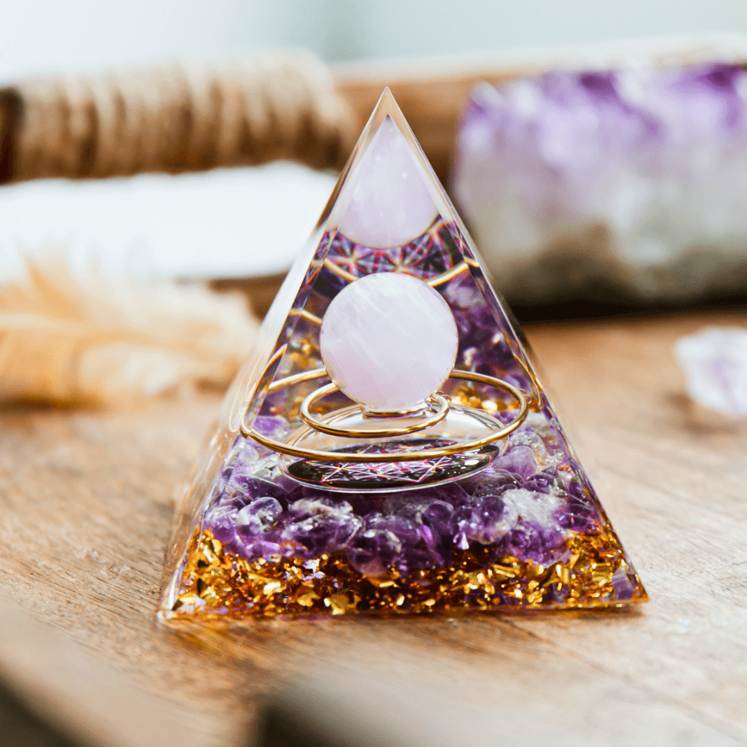 Orgonite piramidal de resina com esfera de cristal, pedras ametista e detalhes dourados.